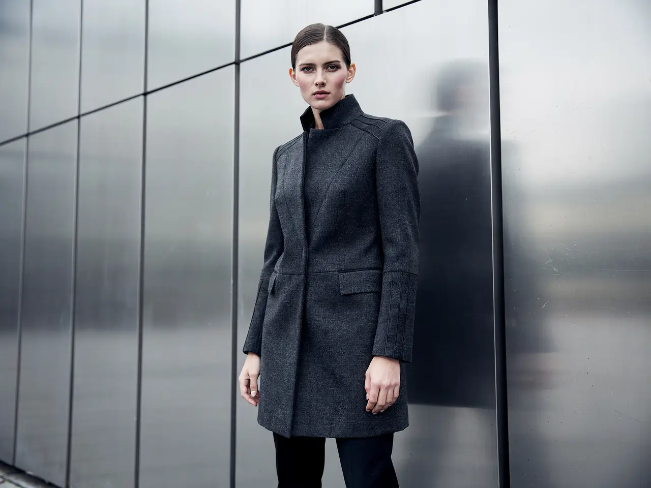 Editorial fashion campaign still of an adult model in a structured coat
